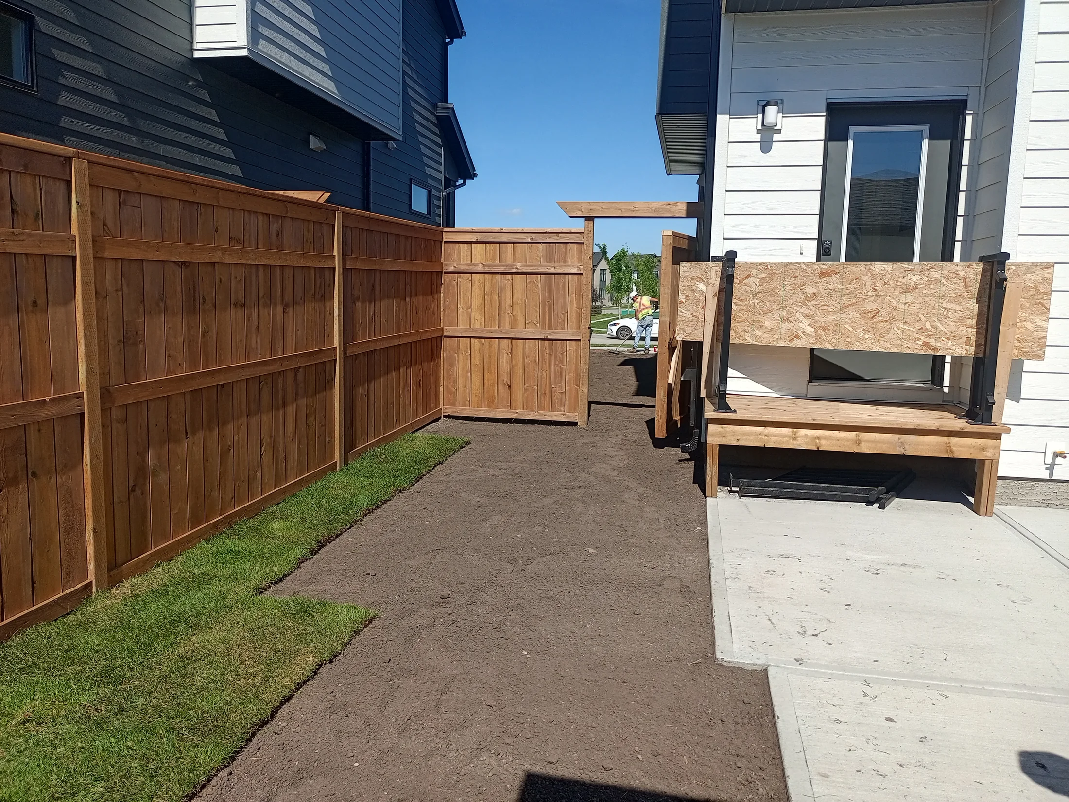 New cedar privacy fence and custom gate beside a Calgary home during landscape installation